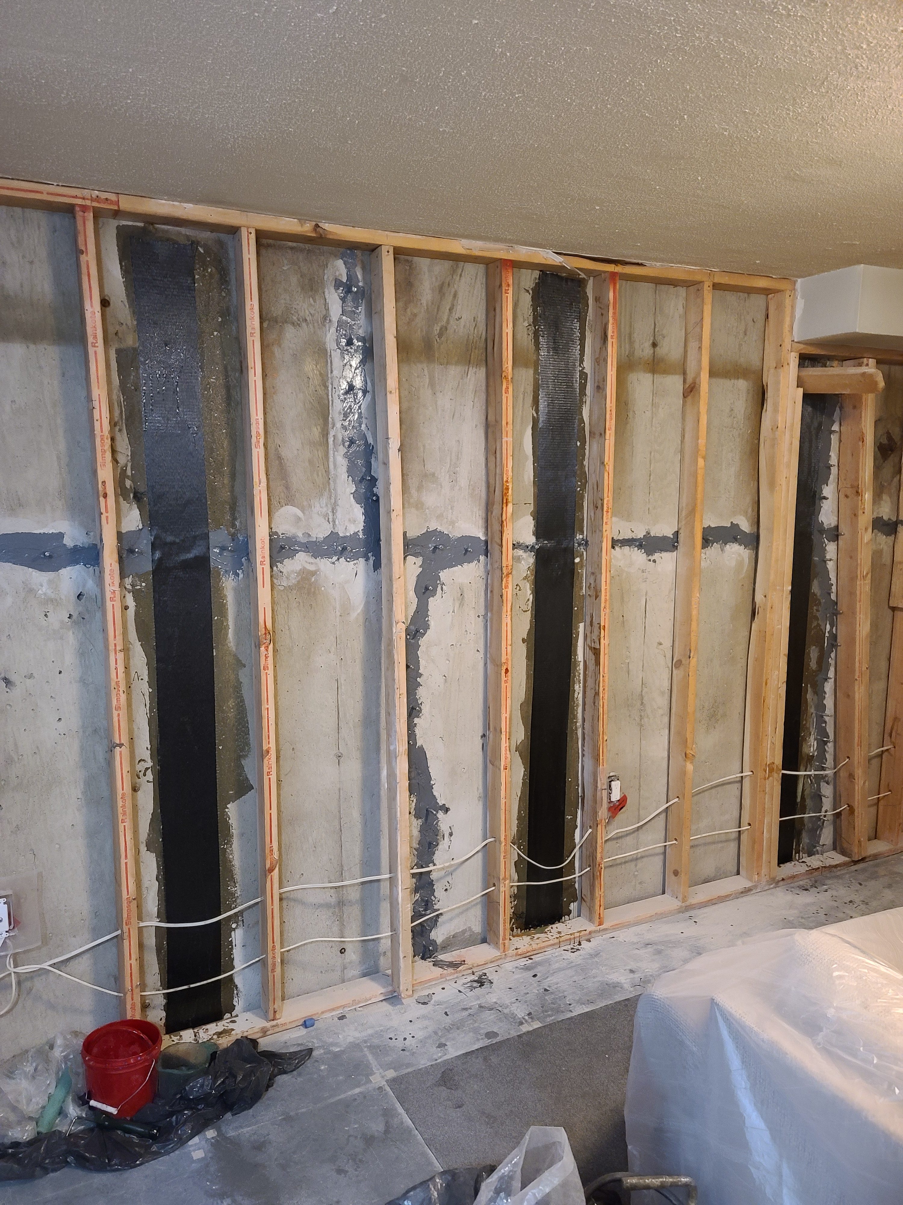 Concrete basement wall with wooden framing and carbon fiber strips applied for foundation repair in Edmonton